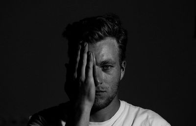 Portrait of young man against black background