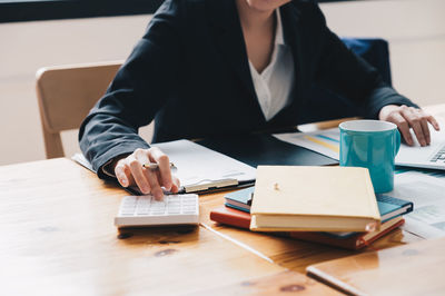 Midsection of woman using mobile phone while sitting on table