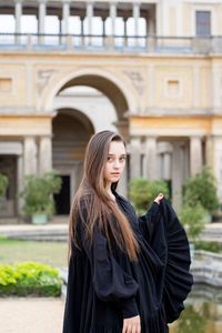 Portrait of woman standing against built structure