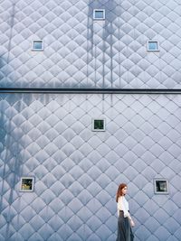 Side view of woman walking against wall