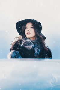Portrait of smiling young woman against snow