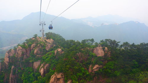 Overhead cable car over mountains against sky