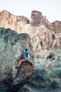 Male climber getting to the top of the boulder in smith rock park