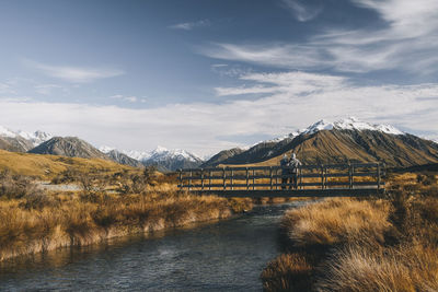 A couple stands in a bridge over a creek lake clearwater, southern alp