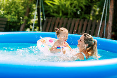 Cheerful healthy mother and daughter play in swimsuits in the pool. time together, summer time