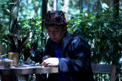 Man sitting on chair against plants