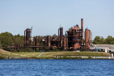 Factory by river against clear sky