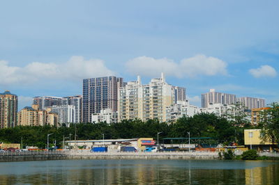 Boats in river by buildings in city against sky