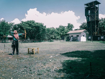 Rear view of man standing on field against building