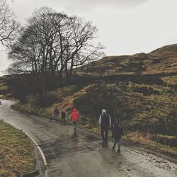 Rear view of people walking on road against sky