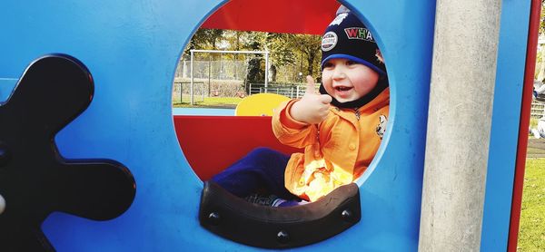 Portrait of happy boy on slide at playground