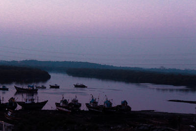 Boats moored in sea against sky during sunset