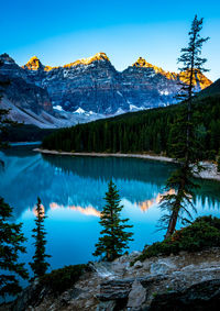 Scenic view of lake and mountains against blue sky