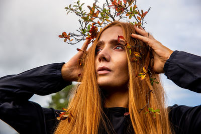 Close-up of woman wearing plant on head looking away while standing outdoors