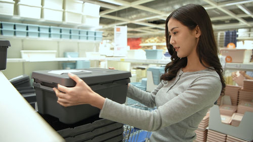 Young woman holding camera while standing in office