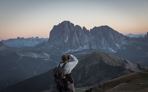 Man photographing on snowcapped mountains against sky