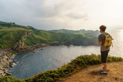 Rear view of man standing on mountain against sky