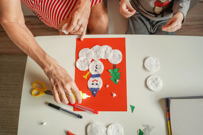 Midsection of grandmother and grandson preparing craft at home