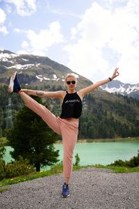 Portrait of woman exercising while standing against mountain range