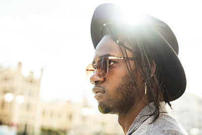 Close-up of young man standing in city against sky