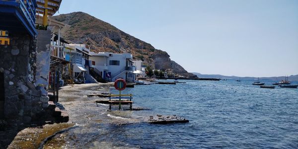 Buildings by sea against clear sky