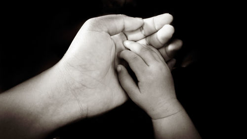 Close-up of baby hands against black background