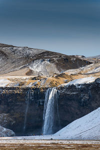 Scenic view of waterfall against sky during winter