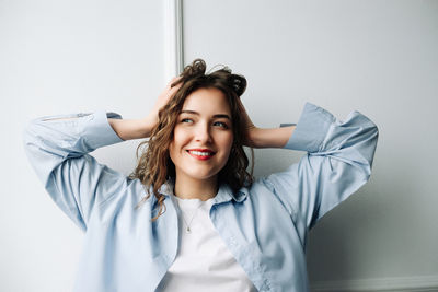 Portrait of young woman standing against wall