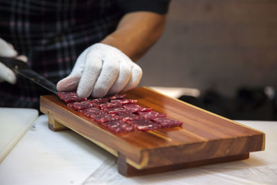 Midsection of man arranging meat on cutting board in kitchen