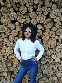 Portrait of smiling young woman standing against firewood