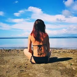 Rear view of woman sitting at beach