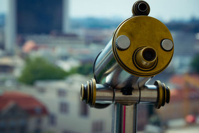 Close-up of coin-operated binoculars against cityscape