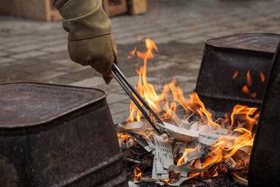 Western raku reduction bins being loaded with pottery using protective gloves and tongs into a fire