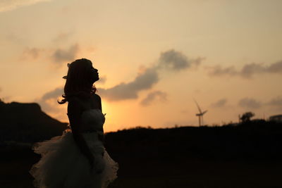 Silhouette of woman  in white dress standing on field