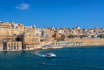 Boats in sea against buildings in city