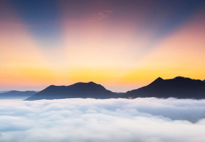 Scenic view of dramatic sky over silhouette mountains during sunset