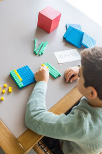 Little boy using the base 10 method to do addition at home