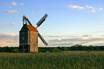 Traditional windmill on field against sky