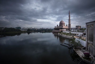 Reflection of buildings in lake against cloudy sky