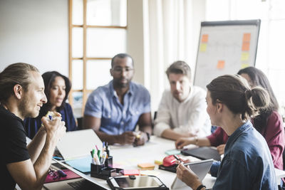 Businesswoman showing diary while explaining business plan to coworkers in meeting at office