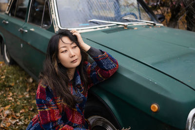 Portrait of young woman near retro car