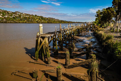 Wooden posts on beach against sky