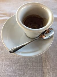 Italian espresso coffee, legendary, white porcelain cup, spoon, closeup, from above, flat lay, table 