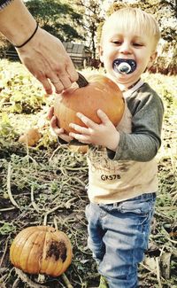 Close-up of boy holding pumpkin at field