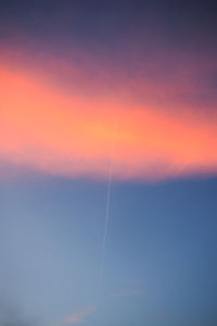 Low angle view of vapor trails in sky during sunset