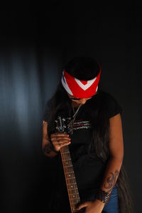 Midsection of man playing guitar against black background