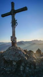 Cross on rock against sky