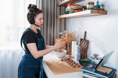 Funny woman making meatballs and talking to her friends via video chat. new normal, social distance