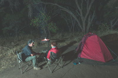 People relaxing in tent at night