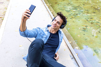 Man listening music while using mobile phone in city